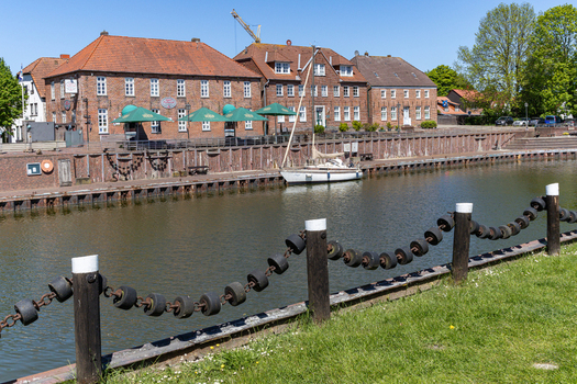 View of historic brick buildings and a sailboat moored in the harbor of Hooksiel under a clear blue sky Wangerland Niedersachsen Germany. View of historic brick buildings and a sailboat moored in the harbor of Hooksiel under a clear blue sky Wangerland Niedersachsen Germany.