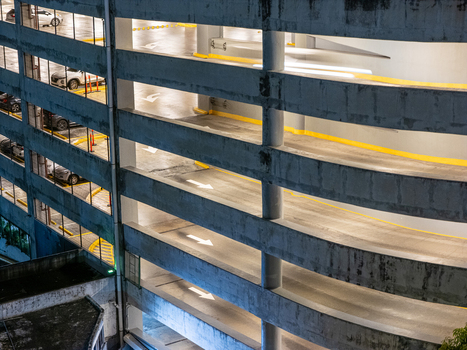 Aerial view of a multi level concrete parking garage ramp with directional arrows and parked cars at night in Santo Domingo Distrito Nacional Dominican Republic. Aerial view of a multi level concrete parking garage ramp with directional arrows and parked cars at night in Santo Domingo Distrito Nacional Dominican Republic.