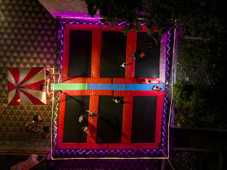 Aerial view of people jumping on trampolines at the GOR Gelarsena Klaten Night Market with vibrant neon lights and a striped tent in Kecamatan Klaten Utara Jawa Tengah Indonesia. Aerial view of people jumping on trampolines at the GOR Gelarsena Klaten Night Market with vibrant neon lights and a striped tent in Kecamatan Klaten Utara Jawa Tengah Indonesia.
