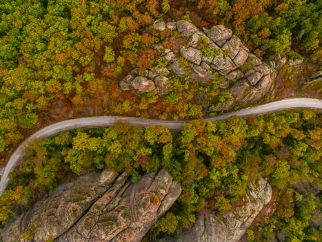Aerial view of the Belogradchik Rocks surrounded by autumn forest with a winding road cutting through the landscape in Belogradchik Vidin Bulgaria. Aerial view of the Belogradchik Rocks surrounded by autumn forest with a winding road cutting through the landscape in Belogradchik Vidin Bulgaria.