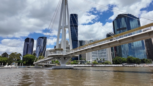 View of the modern Kurilpa Bridge spanning the Brisbane River with skyscrapers in the background under a blue sky in Brisbane Queensland Australia. View of the modern Kurilpa Bridge spanning the Brisbane River with skyscrapers in the background under a blue sky in Brisbane Queensland Australia.