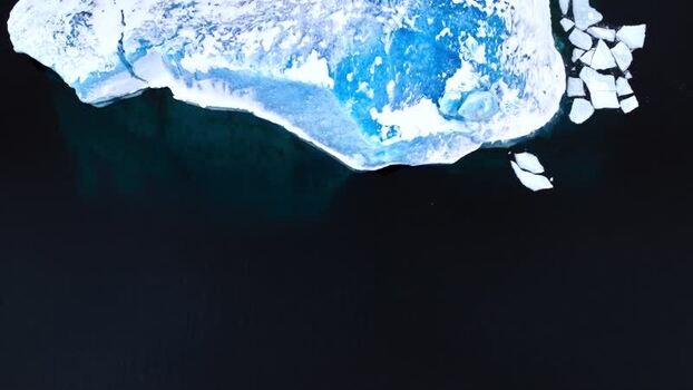 Aerial view of a large iceberg with blue ice in dark water Greenland. Aerial view of a large iceberg with blue ice in dark water Greenland.