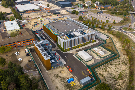 Aerial view of Ark Data Centres at Longcross Park featuring modern industrial buildings cooling infrastructure and surrounding green space in Chertsey England United Kingdom. Aerial view of Ark Data Centres at Longcross Park featuring modern industrial buildings cooling infrastructure and surrounding green space in Chertsey England United Kingdom.