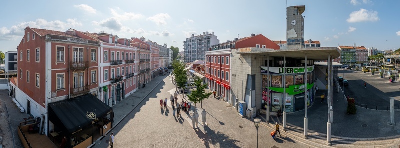 Alges Portugal 25 July 2026 Aerial view of the town square in Alges featuring historic buildings a clock tower and people walking on cobblestone streets under a clear sky.