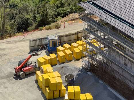 View of a construction site featuring a red telehandler stacks of yellow insulation blocks and scaffolding against a building under construction in Avcilar Istanbul Turkiye. View of a construction site featuring a red telehandler stacks of yellow insulation blocks and scaffolding against a building under construction in Avcilar Istanbul Turkiye.
