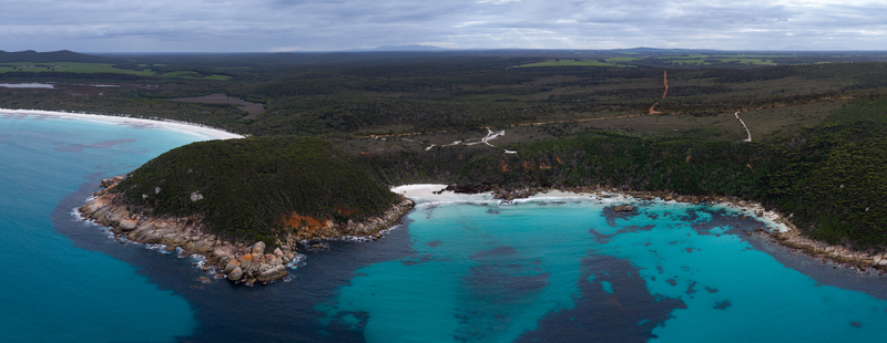 Aerial view of Bettys Beach with turquoise waters rocky headlands and dense coastal vegetation under a cloudy sky in Albany WA Australia. Aerial view of Bettys Beach with turquoise waters rocky headlands and dense coastal vegetation under a cloudy sky in Albany WA Australia.