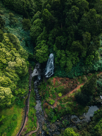Aerial view of a cascading waterfall plunges amidst a vibrant tapestry of emerald trees creating a mesmerizing contrast of power and tranquility Achada Portugal. Aerial view of a cascading waterfall plunges amidst a vibrant tapestry of emerald trees creating a mesmerizing contrast of power and tranquility Achada Portugal.