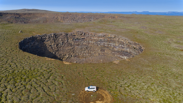 Aerial view of Litla Viti crater with a white SUV parked on the mossy volcanic landscape in Husavik Nordurthing Iceland.