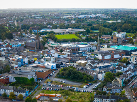 Aerial view of Bangor Harbour and Town featuring church spires dense urban rooftops a green sports field and coastal landscape in Bangor Northern Ireland United Kingdom.