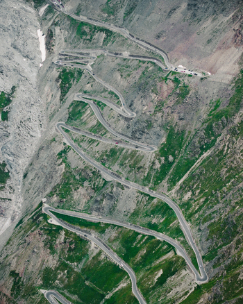 Aerial view of the winding hairpin turns of the Stelvio Pass mountain road carved into the steep rocky slopes in Stilfs Trentino Alto Adige Italy.