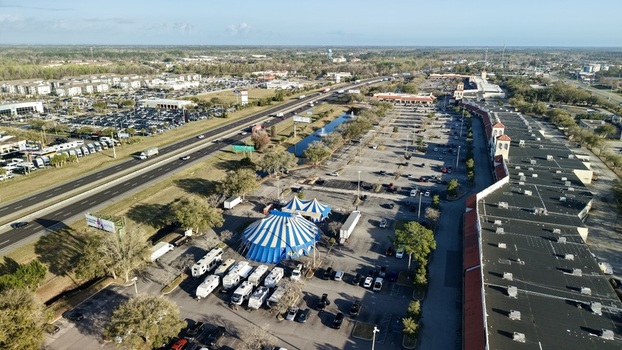 Aerial view of a blue and white circus tent pitched near a highway juxtaposed against the sprawling parking lot and commercial buildings St. Augustine Florida United States. Aerial view of a blue and white circus tent pitched near a highway juxtaposed against the sprawling parking lot and commercial buildings St. Augustine Florida United States.