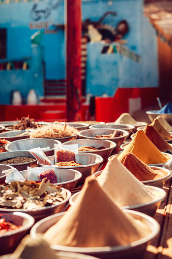 View of colorful spices arranged in metal bowls with conical piles of turmeric and cumin at a traditional market in Aswan Aswan Governorate Egypt. View of colorful spices arranged in metal bowls with conical piles of turmeric and cumin at a traditional market in Aswan Aswan Governorate Egypt.