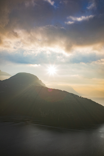 Aerial view of the Swiss Alps with sun rays breaking through clouds over a mountain range and lake in Airolo Ticino Switzerland. Aerial view of the Swiss Alps with sun rays breaking through clouds over a mountain range and lake in Airolo Ticino Switzerland.