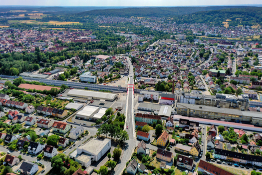 Aerial view of Piastenbrucke crossing railway tracks surrounded by residential houses and industrial buildings under a clear sky in Forchheim Bayern Germany.