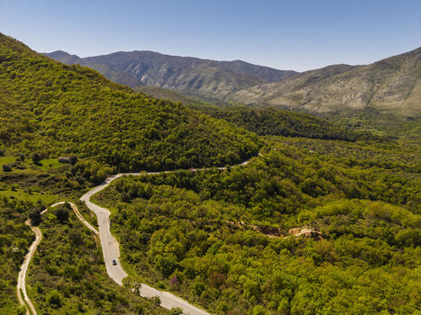 Aerial view of a winding road through the lush green hills of Muzine in Muzina Qarku i Vlores Albania. Aerial view of a winding road through the lush green hills of Muzine in Muzina Qarku i Vlores Albania.