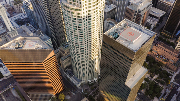 Aerial view of modern skyscrapers and office buildings in the downtown district featuring glass facades rooftop helipads and urban streets below Los Angeles California United States.