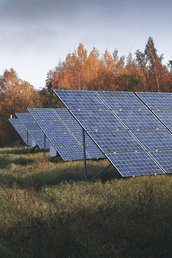 View of solar panels installed in a grassy field with autumn foliage in the background in Otepaa Valga County Estonia. View of solar panels installed in a grassy field with autumn foliage in the background in Otepaa Valga County Estonia.