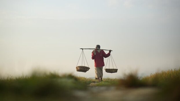 View of a man carrying baskets on a shoulder pole Bangladesh. View of a man carrying baskets on a shoulder pole Bangladesh.