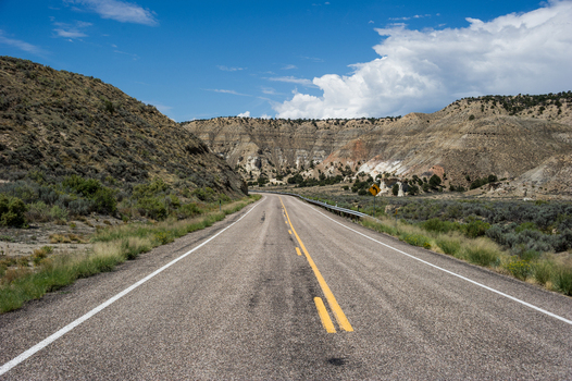 View of a paved road stretching through the arid landscape of Bryce Canyon National Park with distant hills under a blue sky in Utah United States.