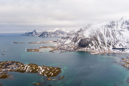 Aerial view of Lofoten featuring snow covered mountains rugged coastline and turquoise waters in Nordland Norway.