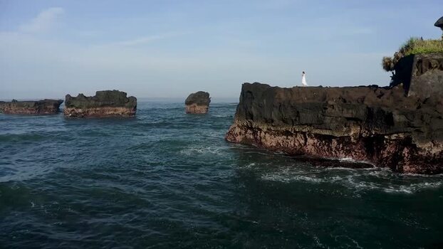 Aerial view of a woman on a cliff by the ocean Indonesia. Aerial view of a woman on a cliff by the ocean Indonesia.