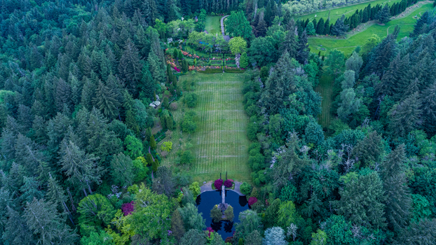 Aerial view of a large estate garden near Northwest Skyline Boulevard with a rectangular lawn and a circular pond surrounded by forest in Portland Oregon United States. Aerial view of a large estate garden near Northwest Skyline Boulevard with a rectangular lawn and a circular pond surrounded by forest in Portland Oregon United States.