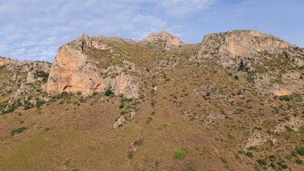 Aerial view of rocky cliffs and grassy slopes in Terrasini Italy.