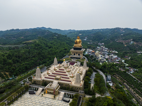 Aerial view of the Fo Guang Shan Buddha Museum with its golden Buddha statue tiered pagodas and courtyards set against lush green hills in Jiuru Township Pingtung County Taiwan. Aerial view of the Fo Guang Shan Buddha Museum with its golden Buddha statue tiered pagodas and courtyards set against lush green hills in Jiuru Township Pingtung County Taiwan.