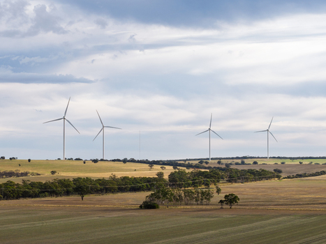 Aerial view of wind turbines standing in vast rural fields with scattered trees under a cloudy sky in Kiata Victoria Australia. Aerial view of wind turbines standing in vast rural fields with scattered trees under a cloudy sky in Kiata Victoria Australia.