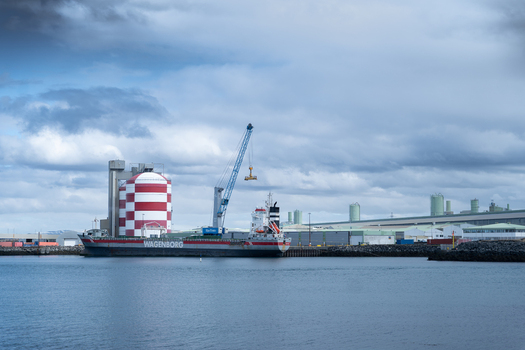 Hafnarfjordur Iceland 17 April 2026 View of a large Wagenborg cargo ship docked at the industrial port with a red and white striped silo and a tall crane under a cloudy sky.