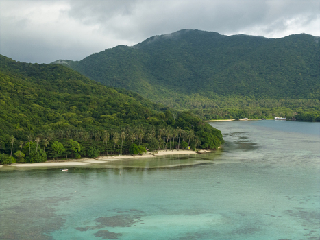 Aerial view of the turquoise waters gently lap against the pristine shores embraced by lush green hills under a cloudy sky Karimunjawa Central Java Indonesia.
