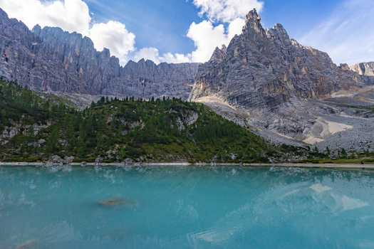 View of Lake Sorapis with its turquoise water reflecting the rugged Dolomite mountains and pine trees in Cortina d Ampezzo Veneto Italy.
