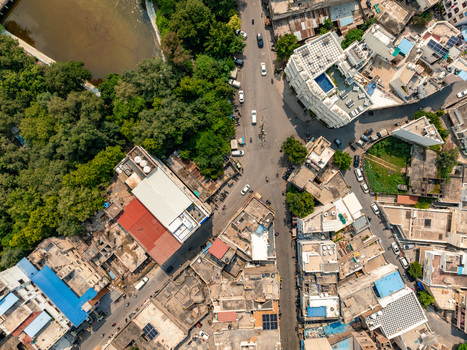 Aerial view of a city street intersection with dense urban architecture rooftops and surrounding greenery in Udaipur Rajasthan India. Aerial view of a city street intersection with dense urban architecture rooftops and surrounding greenery in Udaipur Rajasthan India.