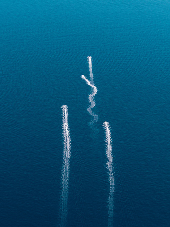 Aerial view of three boat wakes creating white trails on the deep blue Mediterranean Sea near Le Trayas Saint Raphael Provence Alpes Cote d Azur France. Aerial view of three boat wakes creating white trails on the deep blue Mediterranean Sea near Le Trayas Saint Raphael Provence Alpes Cote d Azur France.