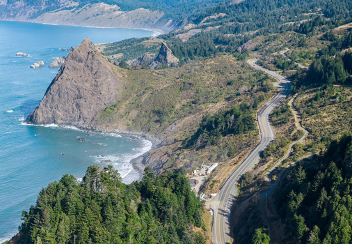 Aerial view of Highway 101 winding along the dramatic cliffs and rugged coastline of the southern Oregon coast near Port Orford Oregon United States. Aerial view of Highway 101 winding along the dramatic cliffs and rugged coastline of the southern Oregon coast near Port Orford Oregon United States.