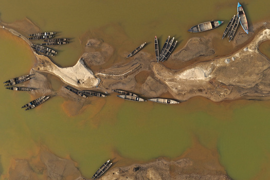 Aerial view of Jadukata River with traditional wooden boats moored along the sandy banks in Sunamganj Sylhet Division Bangladesh. Aerial view of Jadukata River with traditional wooden boats moored along the sandy banks in Sunamganj Sylhet Division Bangladesh.