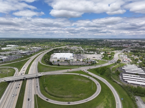Aerial view of a highway interchange and commercial district with large parking lots and green fields under a cloudy sky in Columbus Ohio United States. Aerial view of a highway interchange and commercial district with large parking lots and green fields under a cloudy sky in Columbus Ohio United States.