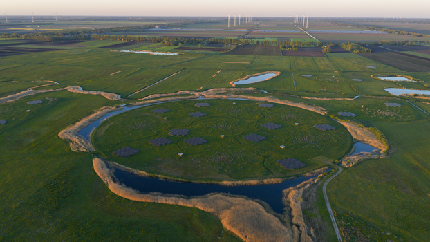 Aerial view of the LOFAR superterp radio telescope station featuring a circular island with antenna arrays surrounded by water and green fields in Buinen Drenthe Netherlands. Aerial view of the LOFAR superterp radio telescope station featuring a circular island with antenna arrays surrounded by water and green fields in Buinen Drenthe Netherlands.