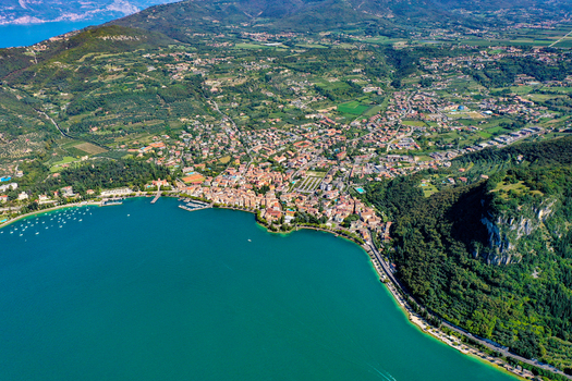 Aerial view of the town on the shores of Lake Garda with lush green hills and turquoise water in Italy. Aerial view of the town on the shores of Lake Garda with lush green hills and turquoise water in Italy.