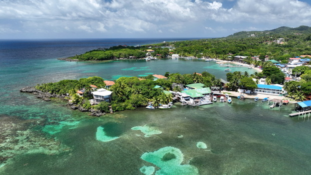 Aerial view of West End featuring turquoise waters coral reefs lush tropical vegetation and coastal buildings in West End Bay Islands Department Honduras. Aerial view of West End featuring turquoise waters coral reefs lush tropical vegetation and coastal buildings in West End Bay Islands Department Honduras.