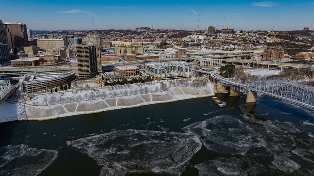 Aerial view of the Cincinnati skyline with snow covered riverbanks and ice floes on the Ohio River under a clear blue sky Cincinnati Ohio United States. Aerial view of the Cincinnati skyline with snow covered riverbanks and ice floes on the Ohio River under a clear blue sky Cincinnati Ohio United States.