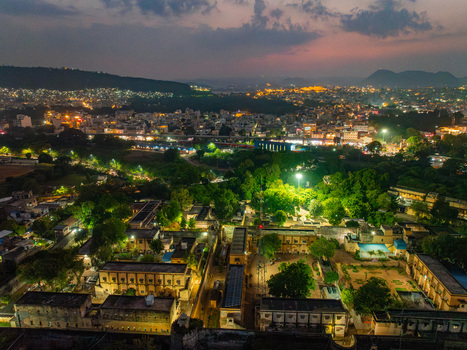 Aerial view of the illuminated cityscape of Udaipur at night featuring historic buildings lush trees and glowing streetlights in Udaipur Rajasthan India. Aerial view of the illuminated cityscape of Udaipur at night featuring historic buildings lush trees and glowing streetlights in Udaipur Rajasthan India.