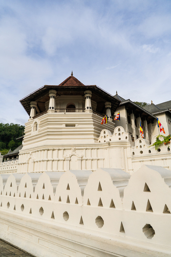 View of the Temple of the Sacred Tooth Relic with its iconic octagonal tower and decorative white walls under a bright sky in Kandy Central Province Sri Lanka. View of the Temple of the Sacred Tooth Relic with its iconic octagonal tower and decorative white walls under a bright sky in Kandy Central Province Sri Lanka.