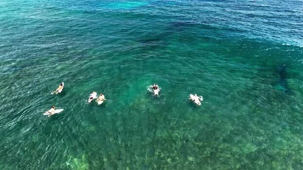 Aerial view of surfers in the turquoise waters of Bali Indonesia.