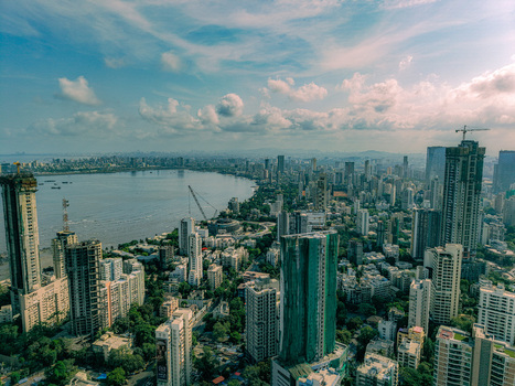 Aerial view of the dense skyline of Mumbai featuring high rise skyscrapers under construction along the curved coastline of Back Bay under a cloudy sky in Mumbai Maharashtra India. Aerial view of the dense skyline of Mumbai featuring high rise skyscrapers under construction along the curved coastline of Back Bay under a cloudy sky in Mumbai Maharashtra India.