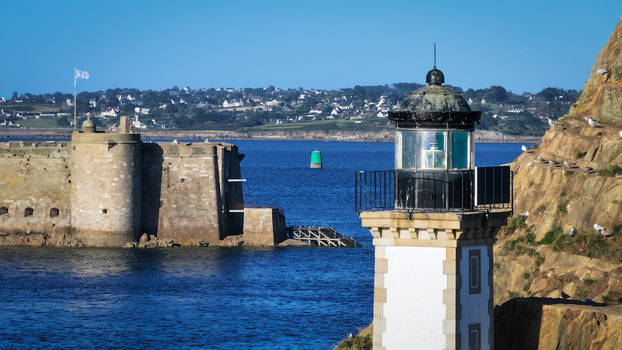Aerial view of a lighthouse standing proudly against the rugged coastline juxtaposed with the formidable Chateau du Taureau Plouezoc h Bretagne France. Aerial view of a lighthouse standing proudly against the rugged coastline juxtaposed with the formidable Chateau du Taureau Plouezoc h Bretagne France.