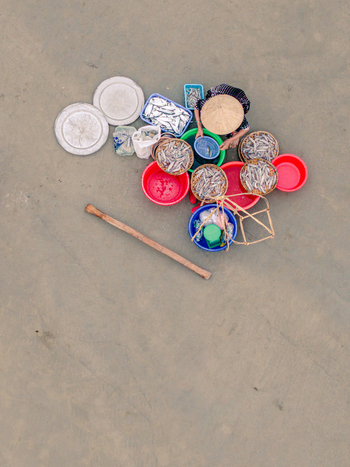 Aerial view of a person wearing a conical hat sorting fresh fish in colorful plastic basins and baskets on a flat surface in Vietnam. Aerial view of a person wearing a conical hat sorting fresh fish in colorful plastic basins and baskets on a flat surface in Vietnam.
