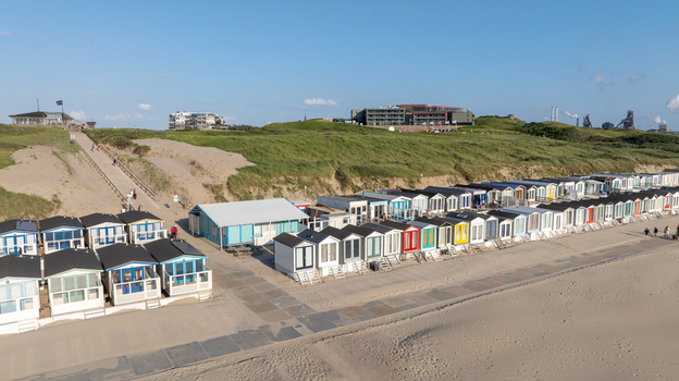 Aerial view of colorful beach huts lined up on the sandy shore of Strand Wijk aan Zee with grassy dunes and buildings in the background Wijk aan Zee North Holland Netherlands. Aerial view of colorful beach huts lined up on the sandy shore of Strand Wijk aan Zee with grassy dunes and buildings in the background Wijk aan Zee North Holland Netherlands.
