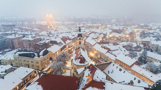 Aerial view of the historic town center of Sremska Mitrovica featuring a church snow covered rooftops and a bridge in the distance in Sremska Mitrovica Vojvodina Serbia.