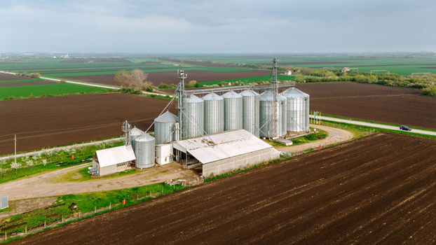 Aerial view of silver silos standing tall against the backdrop of the dark soil and the green fields Sremska Mitrovica Vojvodina Serbia. Aerial view of silver silos standing tall against the backdrop of the dark soil and the green fields Sremska Mitrovica Vojvodina Serbia.